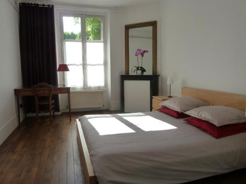 a bedroom with a bed and a desk and a window at Les Carrés in Versailles