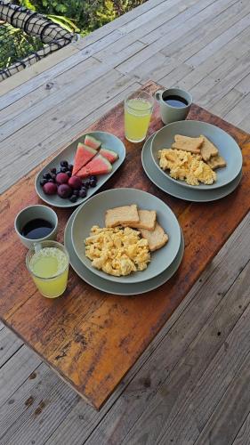 three plates of food on a wooden table with drinks at BAJO EL CIELO Glamping MINCA in Minca