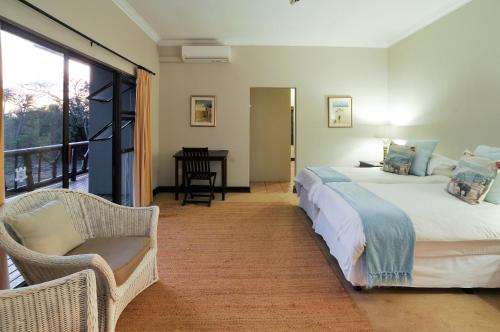 a bedroom with a bed and a balcony with a desk at Hluhluwe River Lodge in Hluhluwe