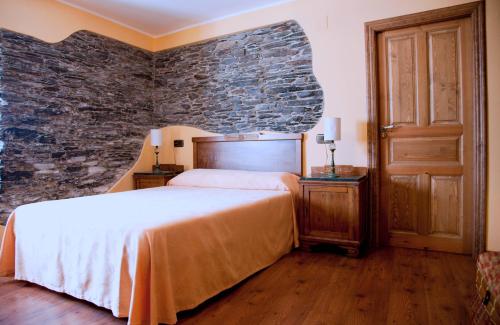 a bedroom with a bed and a stone wall at Apartamentos Rurales Los Galpones in Coaña