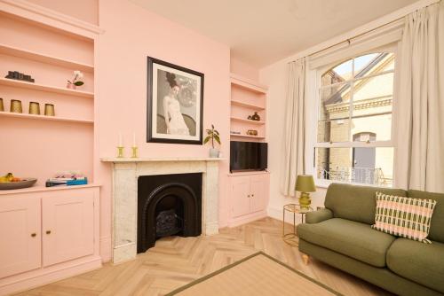 a living room with a fireplace and a green couch at The Corner by the Castle in Rochester
