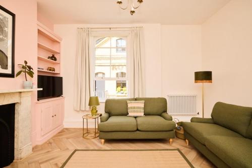 a living room with a green couch and a fireplace at The Corner by the Castle in Rochester