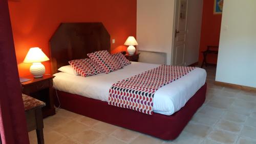 a bedroom with a bed with red walls and two lamps at Hôtel du Donjon in Aulnay