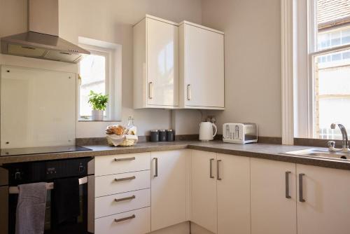 a white kitchen with white cabinets and a sink at The Corner by the Castle in Rochester