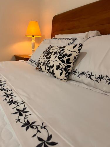 a bed with black and white pillows on it at Jardim Secreto - Itaipava in Itaipava