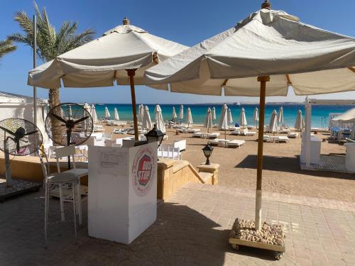a beach with umbrellas and chairs and the ocean at Cozy studio in Azzurra Resort Sahl Hasheesh 65 Sq M in Hurghada
