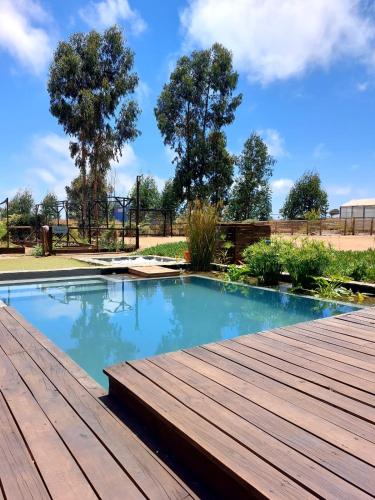 a swimming pool with a wooden deck at Parcela en condominio entre Concon y Maitencillo in Concón