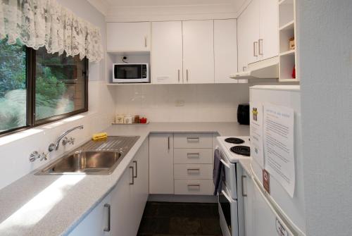 a kitchen with white cabinets and a sink and a window at Marcel Towers Holiday Apartments in Nambucca Heads