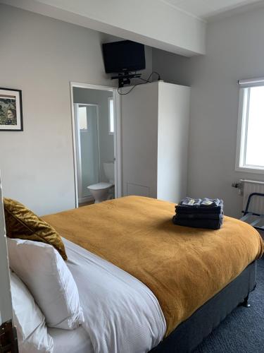 a bedroom with a large bed with a television on the wall at Tuatara Lodge in Invercargill