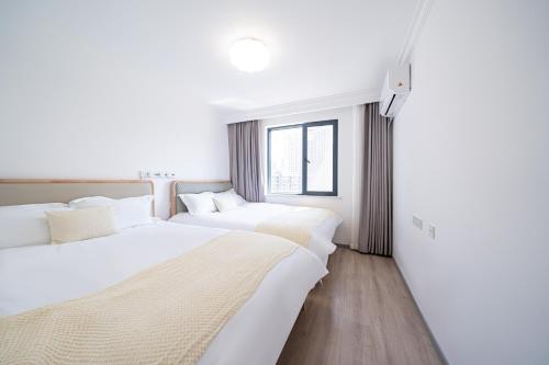 two beds in a hotel room with white walls at Today Aparthotel West Lujiazui Shanghai in Shanghai