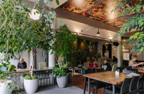 a restaurant with people sitting at tables and plants at Tuatara Lodge in Invercargill