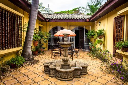 a fountain in a courtyard with chairs and an umbrella at Casa Inti Guesthouse & Lodge in Managua