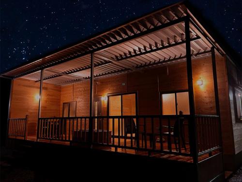 a wooden house with a deck at night at 満天の星空に出会える宿 やんばるtgコテージ in Ujimi