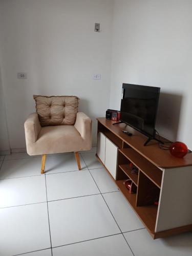 a living room with a chair and a television at Apartamento 2 quartos próximo ao Parque do Povo no centro de Campina Grande in Campina Grande