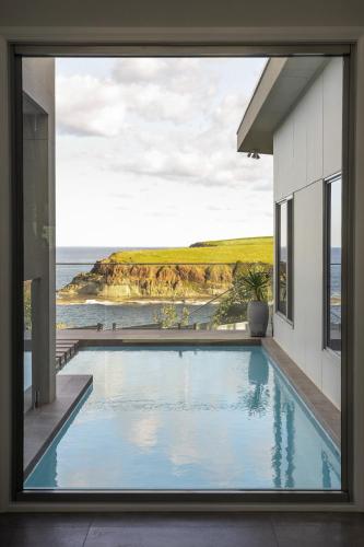 a swimming pool in a house with a view of the ocean at Coastal Indulgence Water Views Romantic Coastal Beach Getaway Kiama in Kiama