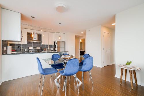 a kitchen and dining room with a glass table and blue chairs at Gorgeous Unit with Beautiful City Views in Vancouver