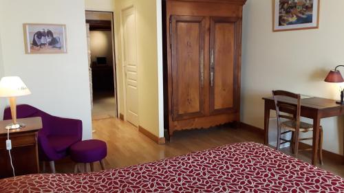 a bedroom with a bed and a desk and a table at Hôtel du Donjon in Aulnay