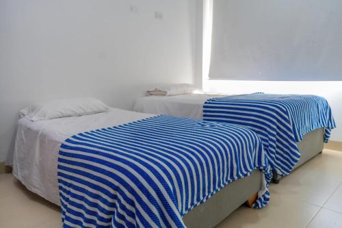 two beds with blue and white sheets in a bedroom at Baleares Apartamentos in Moñitos