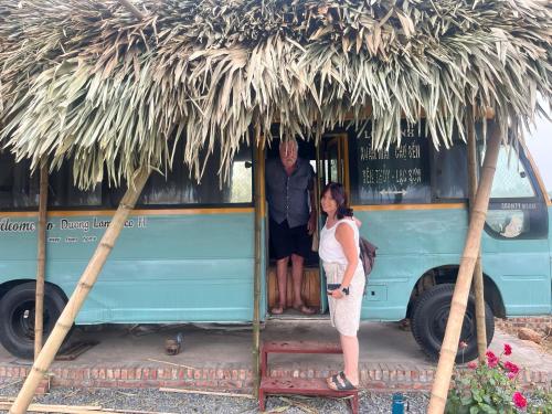 a man and a woman standing in the doorway of a blue bus at Duong Lam Eco Home in Sơn Tây