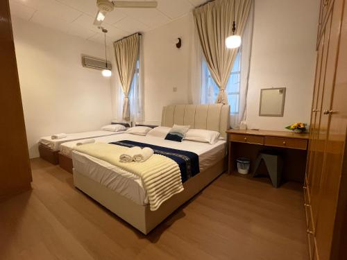 a bedroom with two beds and a desk at C&C Villa Pool Ipoh in Ipoh