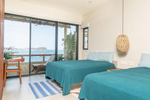 two beds in a room with a view of the ocean at Luxury condo with ocean view & beach access in Tangolunda