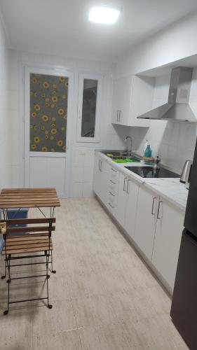 Una cocina con gabinetes blancos y una mesa de madera. en Los abrigos, en Los Abrigos
