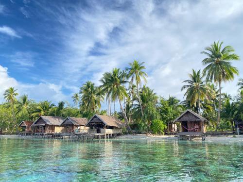 a resort on a tropical beach with palm trees and water at Fam Homestay in Fam