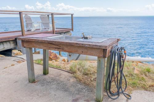 a wooden table with a sink next to the ocean at Belles on Ballow - Lorikeet Lodge - Absolute Waterfront in Amity Point