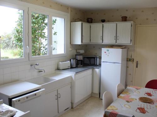 une cuisine avec des armoires blanches et un réfrigérateur blanc dans l'établissement Maison restaurée avec jardin, proche de Périgueux, 2 chambres, Wifi, à 16 km de Brantôme - FR-1-616-69, à Chancelade