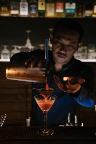 a man pouring a drink into a martini glass at AMANOR Hotel Chiang Mai in Chiang Mai