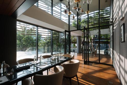 a dining room with a long table and chairs and large windows at AMANOR Hotel Chiang Mai in Chiang Mai
