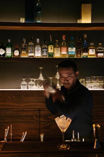 a man standing behind a bar with a martini glass at AMANOR Hotel Chiang Mai in Chiang Mai