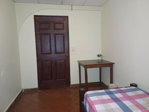 a room with a door and a table and a bed at BlueRock Hostal in David