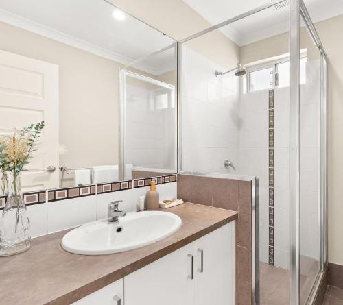 a white bathroom with a sink and a shower at 78 Modern Comforts Quiet Charm 3BR 2BA Parking in Perth