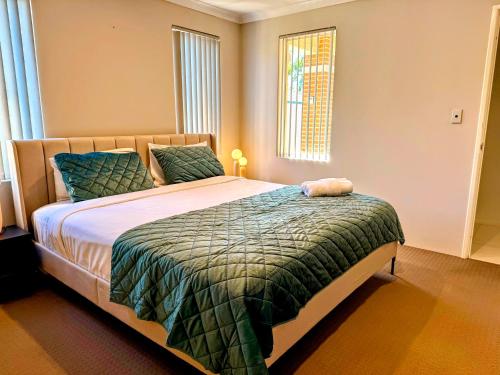a bedroom with a bed with a green comforter at 78 Modern Comforts Quiet Charm 3BR 2BA Parking in Perth