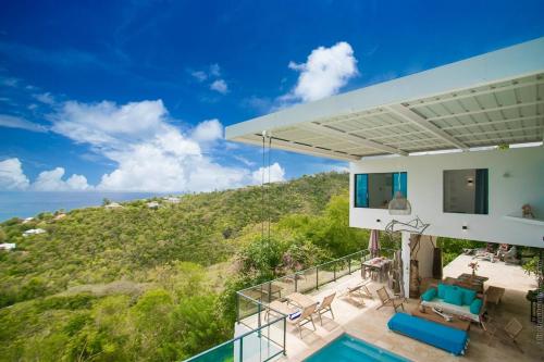 a house with a balcony with a view of the ocean at Villa La Colline - Vue sur Mer des Caraïbes in Schœlcher