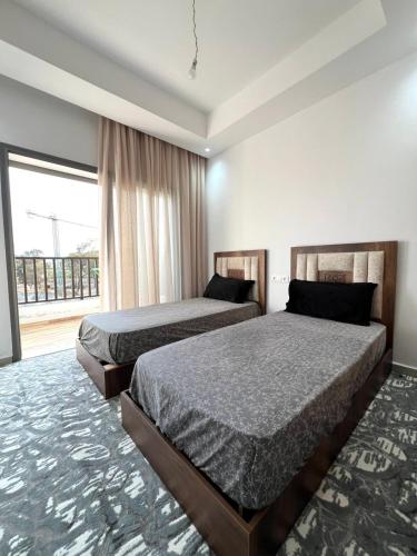 a bedroom with two beds and a large window at Appartement Moderne à CABO Huerto Del Rio in Cabo Negro