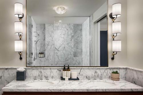 une salle de bain avec deux lavabos et un grand miroir dans l'établissement The Wall Street Hotel by Suiteness, à New York