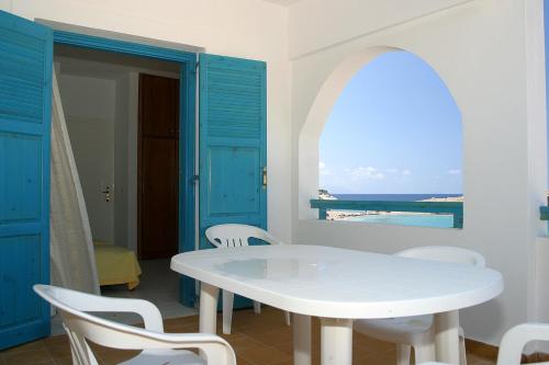 una mesa y sillas blancas en una habitación con ventana en Nefeli Apartments, en Lefkos Karpathou