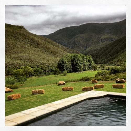 a pool with hay bales in a field with mountains at Pat Busch Mountain Reserve in Robertson