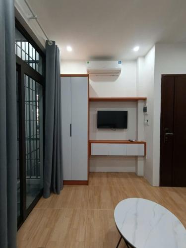 a living room with a tv and a table in a room at Ami Apartment Hà Nội in Hanoi