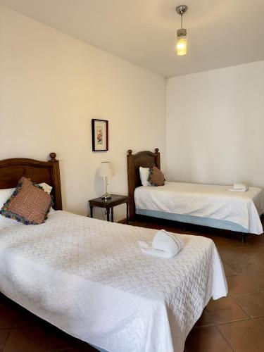 a bedroom with two beds with white sheets and a lamp at El Calvario Lofts in Antigua Guatemala