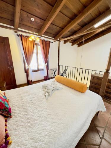 a large white bed in a room with wooden ceilings at El Calvario Lofts in Antigua Guatemala