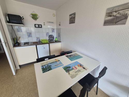 une cuisine blanche avec une table et des chaises blanches dans l'établissement Appartement proche plage avec parking et wifi - 4 personnes - FR-1-672-38, à Merlimont