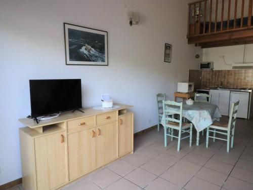 un salon avec une télévision et une table avec des chaises dans l'établissement Maison rénovée 1 étoile avec jardin, 4 couchages - FR-1-738-49, à Saint-Georges-de-Didonne