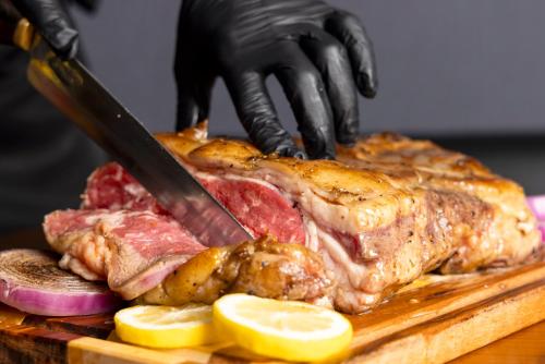 a person cutting a piece of meat with a knife at パプリカホテルです in Kisarazu