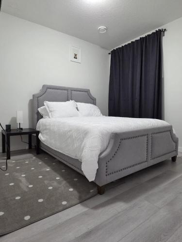 a bedroom with a large bed with white sheets and pillows at Elegant & Cozy 2 Bdrm Basement suite near WEM in Edmonton