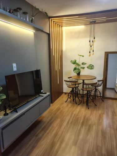 a living room with a tv and a table with chairs at Quarto Privativo em Apto compartilhado in Uberaba