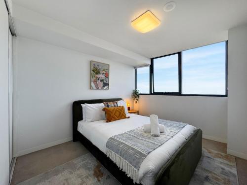 a bedroom with a bed with white walls and windows at Ocean View Modern 2 bedroom with Parking in St Kilda in Melbourne