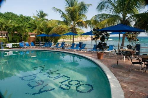 Bolongo Bay Beach Resort All Inclusive في Bolongo: مسبح فيه كراسي ومظلات على شاطئ